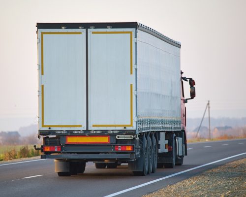 Semi Truck With Cargo Trailer Driving On Highway Hauling Goods In Evening. Delivery Transportation And Logistics Concept